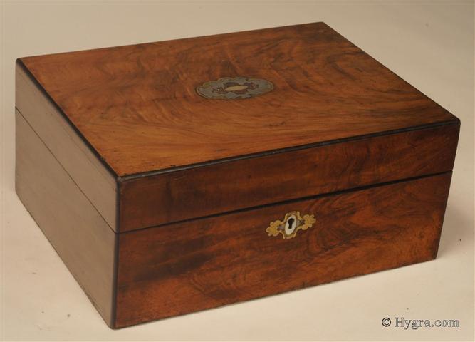 Ref: 636SB: Antique mid Victorian  sewing box veneered with figured walnut accented with brass white metal and mother of pearl and opening to a lift -out tray retaining its original  silver paper covering and supplementary silk covered lids Circa 1860. Enlarge Picture